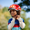 Ein Kind zieht einen woom KIDS Fahrradhelm an
